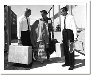 A black and white photo of three men carrying suitcases.
